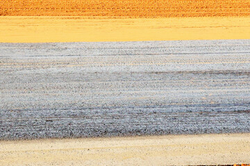 Abstraction of their black strip of asphalt and yellow strip of sand on the side of the road