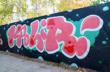 The old wall decorated with paint stains in the style of street art culture. Colorful background of full graffiti painting artwork with bright aerosol outlines on wall. Colored background texture