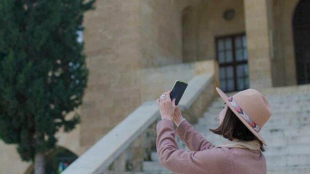 A young woman takes pictures of beautiful views of the city on her phone while traveling through the old town. travel and vacation.