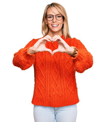 Beautiful blonde woman wearing casual clothes and glasses smiling in love doing heart symbol shape with hands. romantic concept.