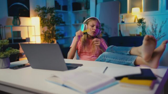 Girl in headset listening to music instead of studying, playing imaginary drums