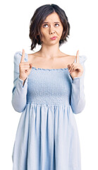 Young beautiful girl wearing casual clothes pointing up looking sad and upset, indicating direction...
