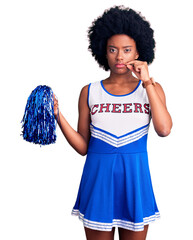 Young african american woman wearing cheerleader uniform holding pompom mouth and lips shut as zip...