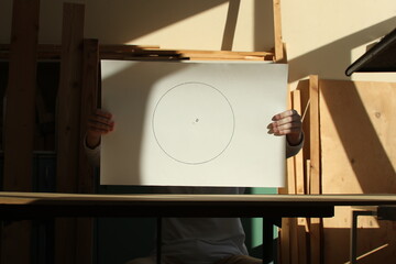 Drawing with circle on a white paper in the hands of a young man and contrasting sunlight. Photo was taken 3 February 2024 year. - 765912021