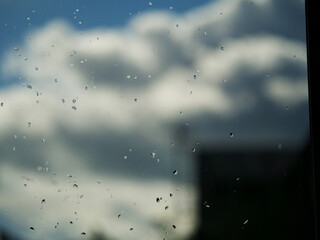 rain drops on a glass window with weather in the background