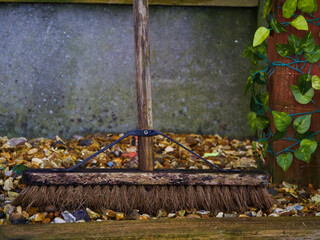 sweeping broom outside with concrete background and leaves