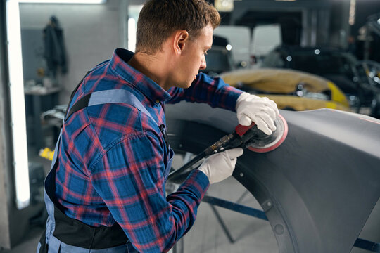 Mechanic working with automobile part, polish surface