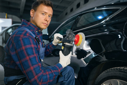Professional worker working with automobile part, polish surface