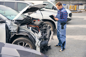 Mechanic on vehicle examination, identification of broken parts