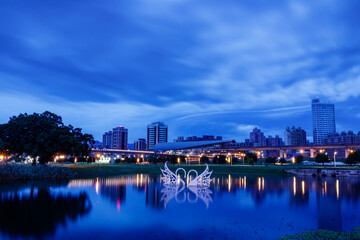 Fototapeta na wymiar Peaceful scenery and reflections during the blue hour before sunrise in early summer near the Sanchong Station of Taoyuan Airport MRT in the New Taipei City Metropolitan Park. 