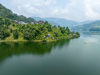 Aerial view of Begnas Lake the third largest lake of Nepal. Wild nature and trees with houses surround the lake, typical Nepalese boats can be seen in the water