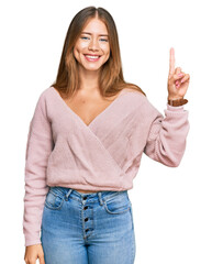 Beautiful blonde woman wearing casual winter pink sweater showing and pointing up with finger number one while smiling confident and happy.