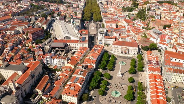 Aerial Tilt Up Shot Of Praca Dom Pedro Iv Amidst Roofed Houses In City Against Clear Sky On Sunny Day - Lisbon, Portugal