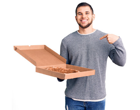 Young handsome man holding delivery italian pizza pointing finger to one self smiling happy and proud