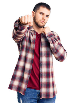 Young handsome man wearing casual shirt punching fist to fight, aggressive and angry attack, threat and violence