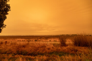 Looking West Across the Dry Former Salt Ponds in Redwood City, California; Orange Smoke Filled Skies from Nearby Out of Control Wildfires Caused by Drought and Climate Change - 765935220