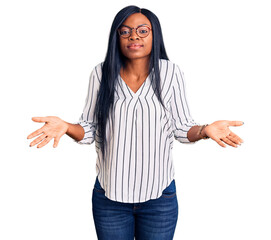 Young african american woman wearing casual clothes and glasses clueless and confused with open...
