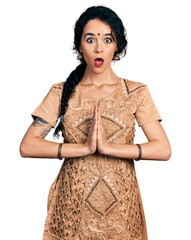 Young indian woman doing anjali mudra afraid and shocked with surprise and amazed expression, fear...