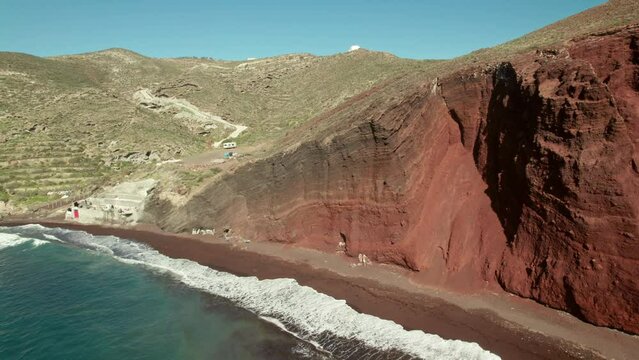 Santorini red sand beach drone flying backwards