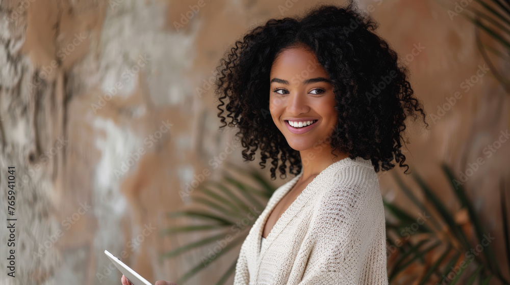 Wall mural beautiful modern woman smiling at camera and using a tablet in her hands.