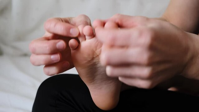 The mother is doing massage of foot for child. Counting and touching the toes. Mom stroking and tickling the kid. Gentle tactile contact. Love atmosphere. Happy moments of motherhood and childhood