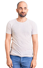 Young handsome man wearing casual t shirt smiling looking to the side and staring away thinking.