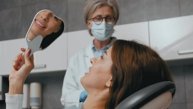 Dental Procedure Discussion: Dentist Explains Treatment while Woman Admires Her Beautiful Teeth