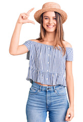 Obraz na płótnie Canvas Young beautiful girl wearing hat and t shirt smiling and confident gesturing with hand doing small size sign with fingers looking and the camera. measure concept.