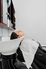 Latina woman in a beauty salon, hair washing. Copy space.