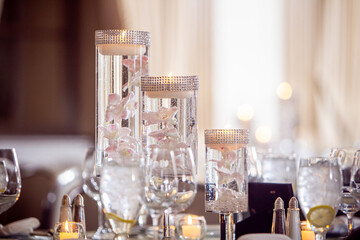 Evening event table decor with floating candles in glass vase and pink orchids - obrazy, fototapety, plakaty