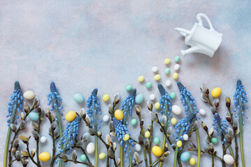 Decorative Easter background with muscari flowers and willow branches, watering can and candy eggs, copy space