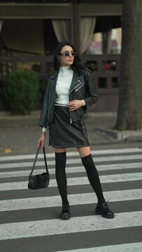 Fashionable woman crosses street, her black leather suit conveys essence of urban style. Concept of Urban Style Confidence