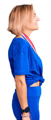 Fototapeta premium Young blonde woman wearing winner medals looking to side, relax profile pose with natural face with confident smile.