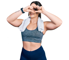 Young hispanic girl wearing sportswear and towel doing heart shape with hand and fingers smiling looking through sign