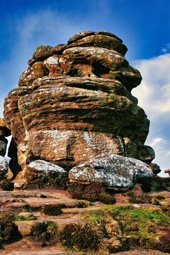 Majestic rock formation under blue sky with clouds, showcasing natural erosion and geological layers at Brimham Rocks, in North Yorkshire