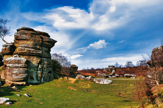 Scenic view of rock formations and lush greenery under a blue sky with wispy clouds at Brimham Rocks, in North Yorkshire