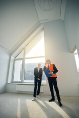Client and contractor standing in room and looking up
