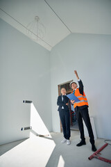 Female client and male architect standing in empty room