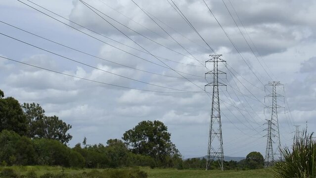 Wide shot of Australian overhead, high tension, high-voltage transmission power-lines and towers on a cloudy day