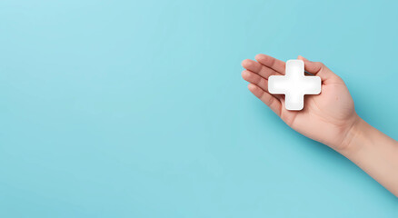 Hand holding a medical cross icon on a blue background