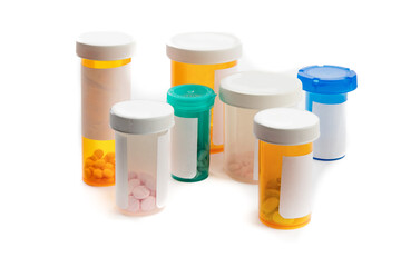 a group of multi colored plastic pill bottles with caps on with blank labels isolated on white