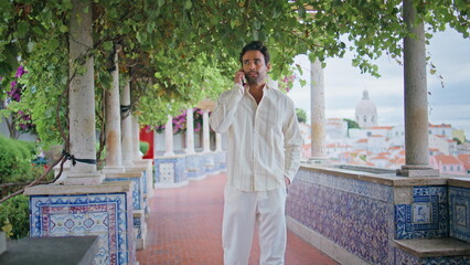 Handsome guy calling cellphone at city view balcony. Tanned macho talking phone