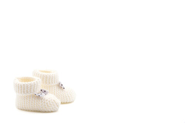 White crochet baby booties with black polka dot bows isolated on a white background. Handmade baby...