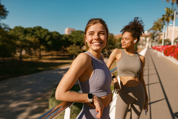 Fototapeta na wymiar Smiling female sportswomen have a rest after morning jogging outdoors and looks away