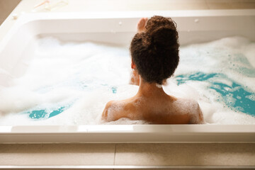 Woman enjoying a bubble bath in a jacuzzi tub filled with water