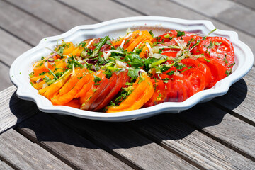 View of a colorful heirloom tomato slice salad with fresh herbs on a platter in Provence, France - 765993667