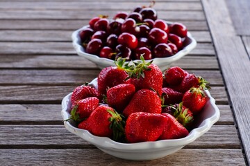 Bowl of fresh cherries and bowl of fresh strawberries in summer - 765993818