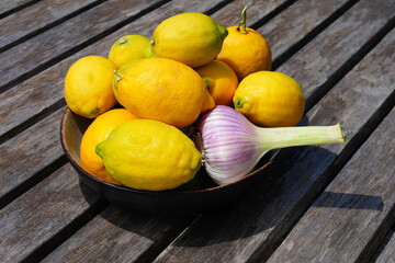 Bowl of fresh lemons with a head of garlic - 765994007