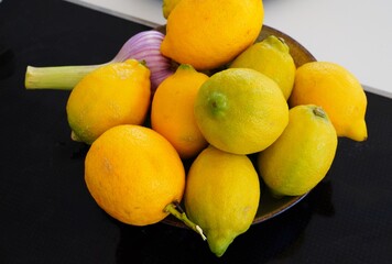 Bowl of fresh lemons with a head of garlic - 765994021