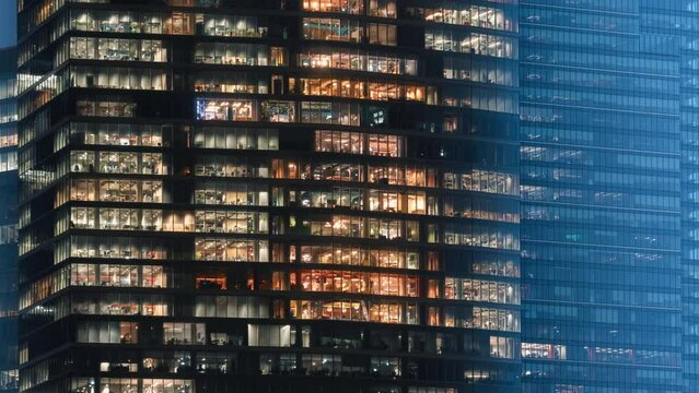 Day to night time-lapse timeslice effect blinking office windows lights, high-rise glass skyscraper business building in city downtown, non-stop work, turn on and off, endless work without breaks